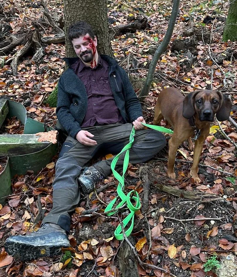 Realistisch geschminkte Verletzung: Jäger mit seinem Hund im Trainingsszenario im Wald