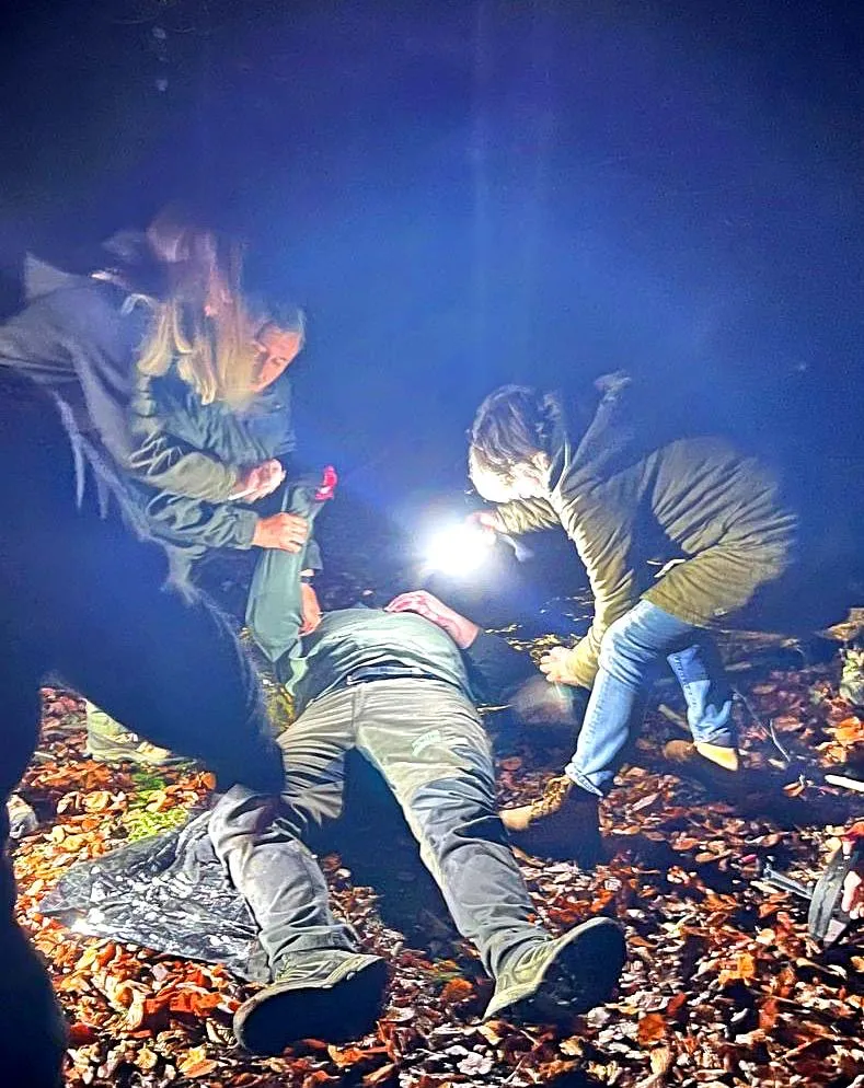 Nächtliches Rettungsszenario: Teilnehmer versorgen einen Verletzten im Gelände bei Taschenlampenlicht